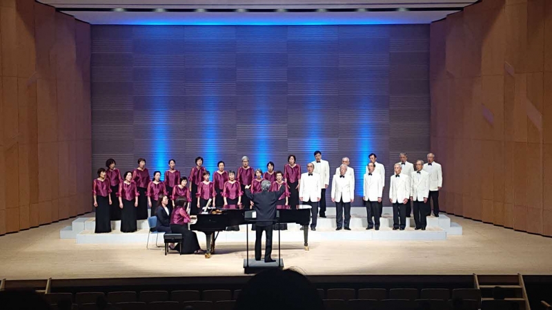 玉名市民合唱団第64回定期演奏会 ピアノの演奏に合わせて26名が合唱している写真