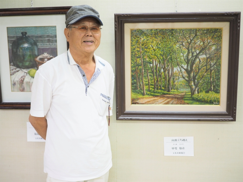 玉名美術協会小品展の絵画をバックに撮影した写真