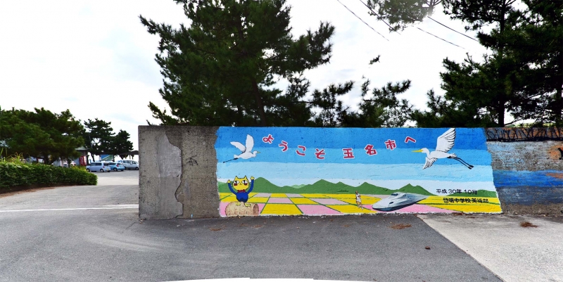 「ようこそ玉名市へ」と文字が書いてあり、タマにゃん、シラサギが飛ぶ玉名平野の水田、九州新幹線が描かれている壁画の写真