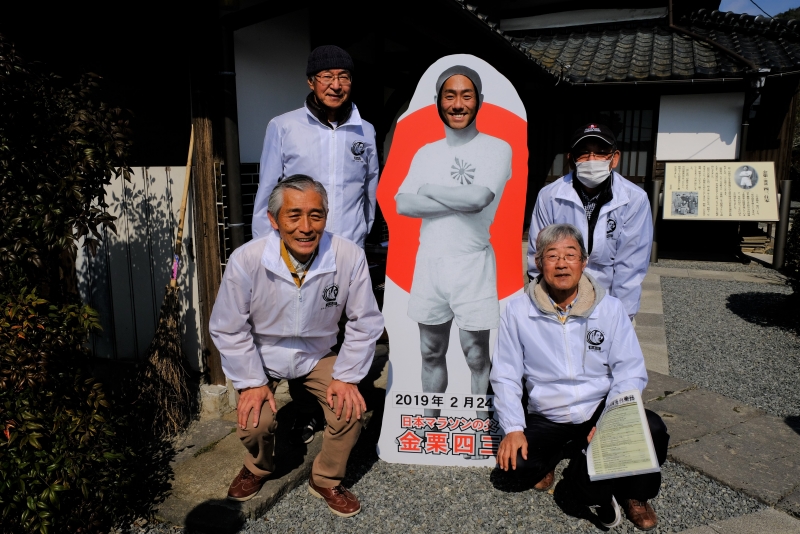 金栗さん顔出しパネルに顔を出した中村勘九郎さんと小田地区4名(男性)の写真