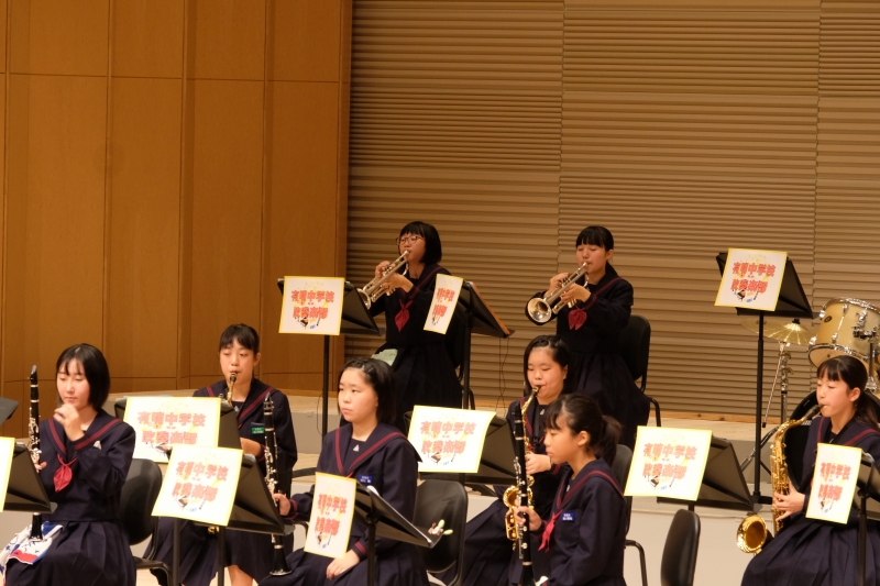 有明中学校がホールで演奏している写真